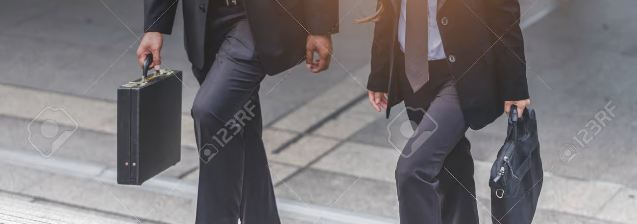 Two business people walking outdoors carrying briefcases