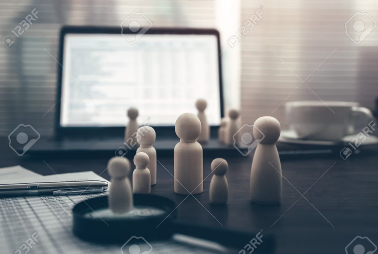 Wooden figures representing a team beside a laptop on a desk