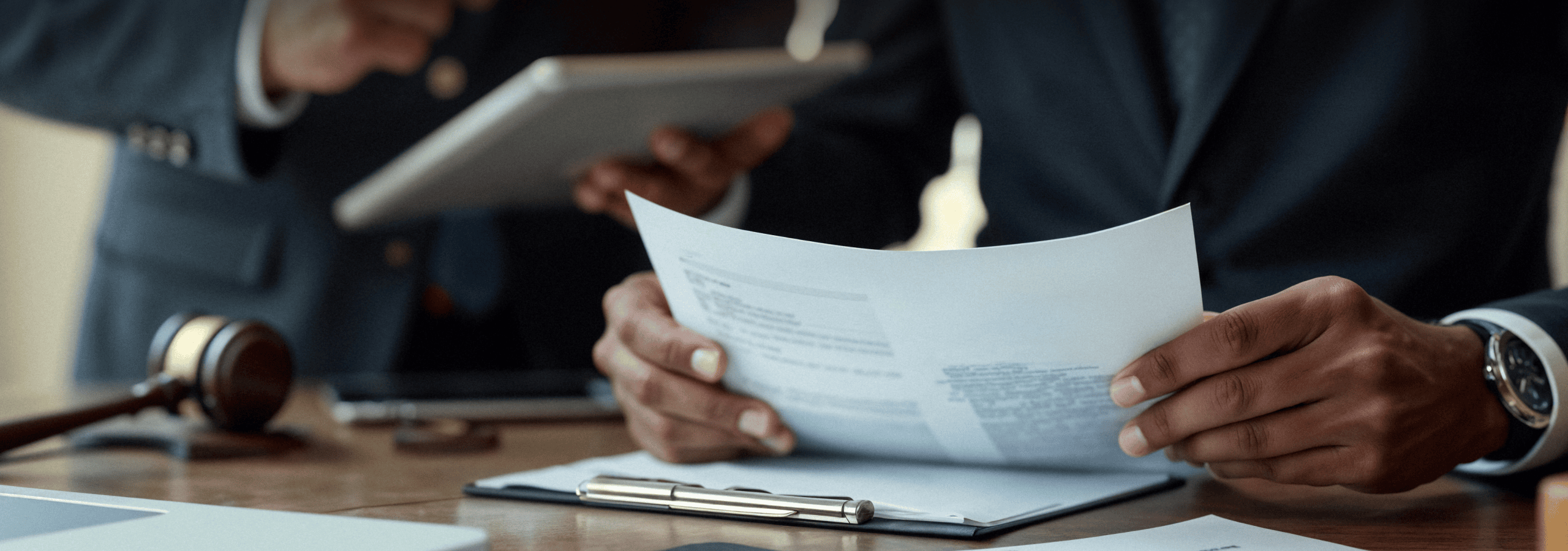 Lawyer reviewing documents with a gavel and tablet on the desk
